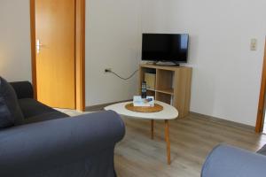 sala de estar con sofá y mesa con TV en Gästehaus Sulsdorf - Adults only, en Sulsdorf auf Fehmarn