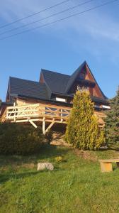 a house with a black roof on a green field at Willa Janosik in Witów