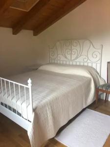 ein weißes Bett mit einer weißen Decke und einem Stuhl in der Unterkunft Barcola mare apartment in Triest