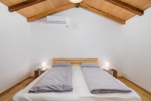 - 2 lits dans une chambre dotée de plafonds en bois dans l'établissement Apartment Ursula, à Lopar