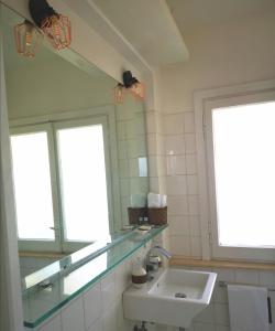a bathroom with a sink and a mirror and two windows at Attico LUX in Lido di Ostia