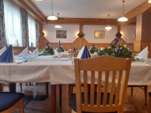 a dining room with a long table with chairs and flowers at Gasthof Jauk-Hartner in Sankt Johann im Saggautal