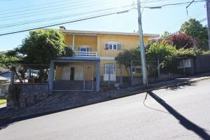 una casa amarilla al lado de una calle en Dália 1 - My Home Temporada, en Gramado