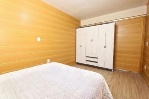 1 dormitorio con 1 cama y pared de madera en Dália 1 - My Home Temporada, en Gramado