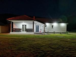 a small white house at night with a yard at Drinska kućica in Ljubovija