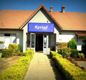 a blue and white building with a sign on the front of it at Kyriad Chantilly Sud - Luzarches in Chaumontel