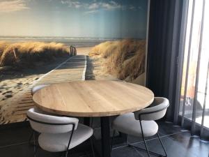 uma mesa e cadeiras num quarto com uma pintura de uma praia em BLOC 79/ THREE em Knokke-Heist