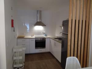 uma cozinha com armários brancos e um frigorífico preto em Apartamentos Areia e Mar Norte em Vila Praia de Âncora