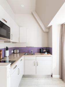 a white kitchen with white cabinets and appliances at limehome Berlin Chausseestraße in Berlin