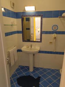 baño azul y blanco con lavabo y espejo en Villa Flavia - Adults Only, en Ponza