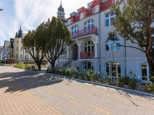 a building on a street with trees in front of it at VacationClub – Wisus Apartament 19 in Świnoujście