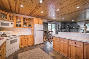 a kitchen with wooden cabinets and a white refrigerator at Rockaway Beach Hideaway with Hot Tub and Fireplace! in Rockaway Beach