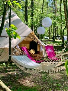 a hammock with a tent in a forest at Caravana Juliana - Glamping in Swaderki