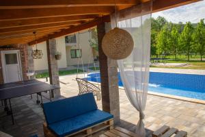 eine Terrasse mit einem blauen Stuhl, einem Tisch und einem Pool in der Unterkunft Holiday Home Faruk in Račić