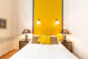 a bedroom with a white bed with yellow walls at Sourire Boutique Hôtel Particulier in Paris