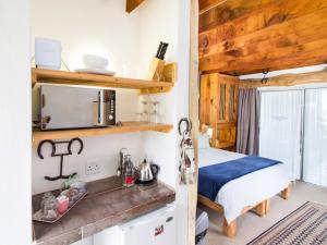 a bedroom with a bed and a kitchen with a microwave at TNiqua Stable Inn in Plettenberg Bay +13 photos