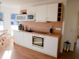 cocina con armarios blancos y fogones en Reethaus Boddenblick - Apt. 09, en Alt Reddevitz