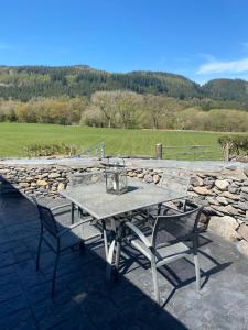 a table and chairs on a patio with a stone wall at Tyddyn Bach Barn in Betws-y-coed