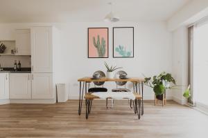 - une cuisine blanche avec une table et des chaises en bois dans l'établissement Ocean 1- Sea View apartment, Fistral Beach Newquay, à Newquay