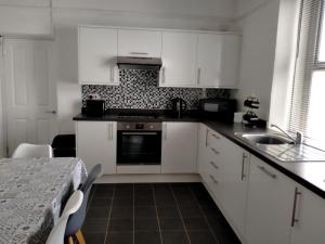 a kitchen with white cabinets and a sink and a table at The Old Post Office in Morriston