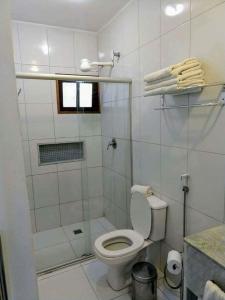 a white bathroom with a toilet and a shower at Pousada Guaratiba in Prado