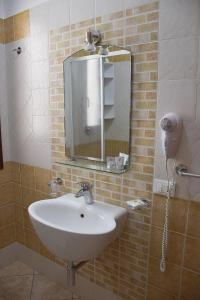 a bathroom with a sink and a mirror at Hotel Sikania in San Vito lo Capo
