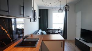 a kitchen with a sink and a living room at Apartament 47 Letnica in Gdańsk