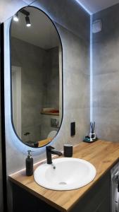 lavabo en el baño con un espejo grande encima. en Apartament 47 Letnica, en Gdansk