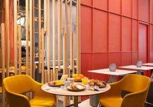 a dining room with two tables and yellow chairs at B&B Hotel Milano City Center Duomo in Milan