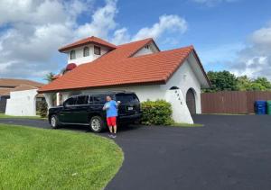 Un uomo in piedi davanti a una macchina davanti a una casa di Bella Stanza a Miami