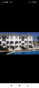 a large white building with a swimming pool in front of it at Apartamento vacacional máximo 4 personas in Novo Sancti Petri