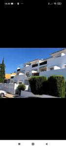 a large white building with bushes in front of it at Apartamento vacacional máximo 4 personas in Novo Sancti Petri +11 photos