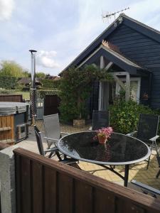 a patio with a table and chairs on a deck at Beautiful barn with private log fired hot tub in Maidstone