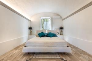 una camera da letto bianca con un letto con cuscini blu di Isola del Pittore casa indipendente in Villa Storica a Grassina Altre 49 foto