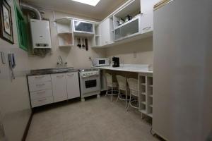 una pequeña cocina con armarios blancos y fregadero en Morada do Lago - My Home Temporada, en Gramado
