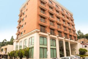 杜伊塔马Hotel Dinastia Real的一座高大的红砖建筑,前面有汽车停放