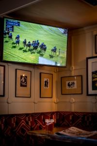 Un televisor en una pared con una carrera de caballos. en The Queen's Arms, en Hungerford