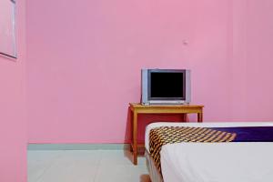 1 dormitorio con paredes rosas y TV en una mesa en OYO 90268 Aliyah Syariah, en Yakarta