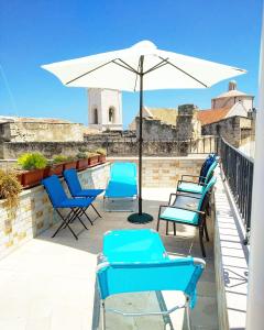 un grupo de sillas y una sombrilla en el balcón en C'era una Volta Apartments, en Polignano a Mare