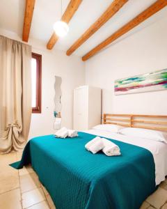 1 dormitorio con 1 cama azul y 2 toallas en C'era una Volta Apartments, en Polignano a Mare
