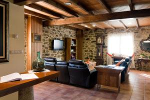 a living room with leather chairs and a television at A Casa do Folgo Turismo Rural in Negreira
