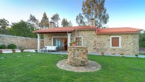 a stone house with a stone pillar in a yard at Casa Portolago in Carballo