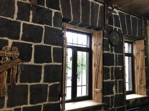 Old Gyumri Guest House / Հին Գյումրի հյուրատուն في غيومري: ساعة على جدار حجري مع نافذتين