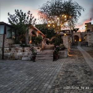 a house with a brick walkway and stairs at sunset at Cappadocia Caves Hotel in Göreme