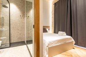 a bathroom with a bed and a glass shower at Santa Clara Suites Sevilla in Seville