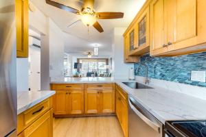 a kitchen with wooden cabinets and a ceiling fan at Menehune Shores in Kihei