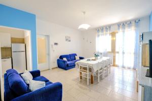 a kitchen and living room with a table and blue chairs at Casa Marina in Torre San Giovanni Ugento