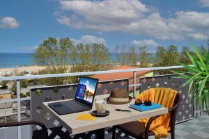 un computer portatile seduto su un tavolo sul balcone di Hotel Gaston a Rimini