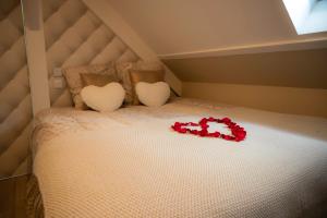 ein Bett mit zwei Herzkissen und roten Rosen darauf in der Unterkunft Le Loft de Zoé in Saint-Sylvain