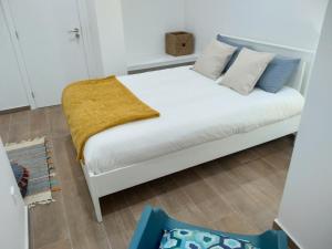 Un dormitorio con una cama blanca con una manta amarilla. en Apartamentos Areia e Mar Norte, en Vila Praia de Âncora